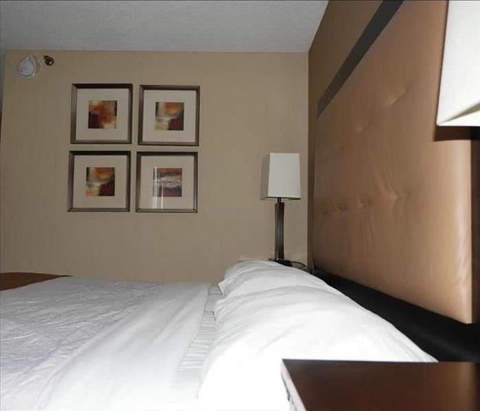 The same hotel room with a new bed and completely renovated walls and ceilings.